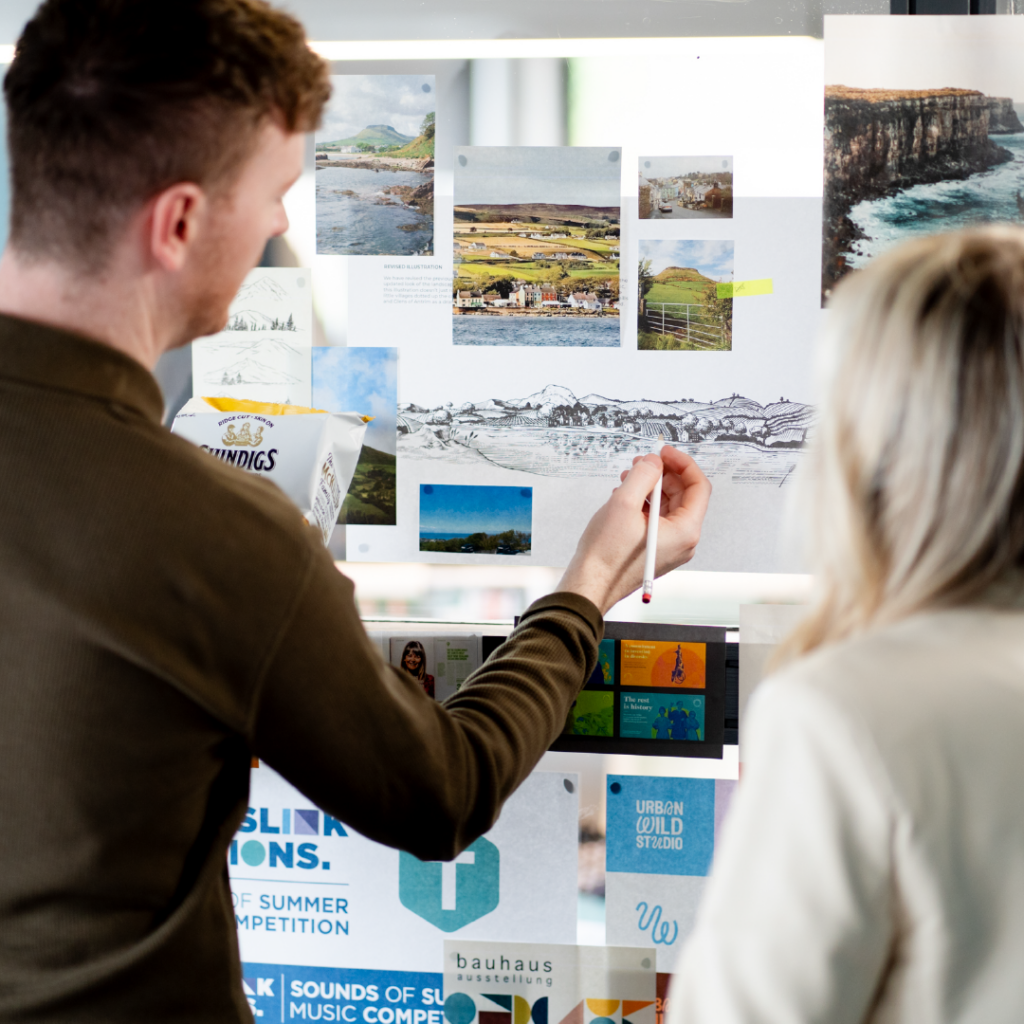 Designers discussing design ideas and sketching ideas onto printed designs on wall